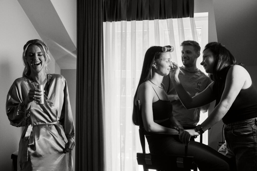 Makijażystka wykonuje profesjonalny makijaż modelki przed sesją fotograficzną w studiu.