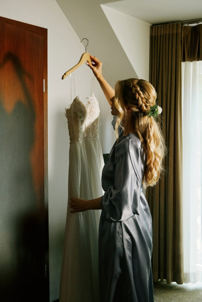 Szczęśliwa kobieta trzymająca suknię ślubną w eleganckim studio.