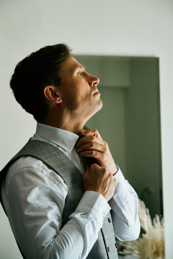 Portret mężczyzny w eleganckim stroju, przygotowującego się do wydarzenia, w nowoczesnym studio.