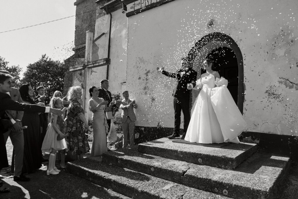 Uroczystość ślubna przed kościołem, szczęśliwa para młoda i goście w trakcie bukietu papierosów.