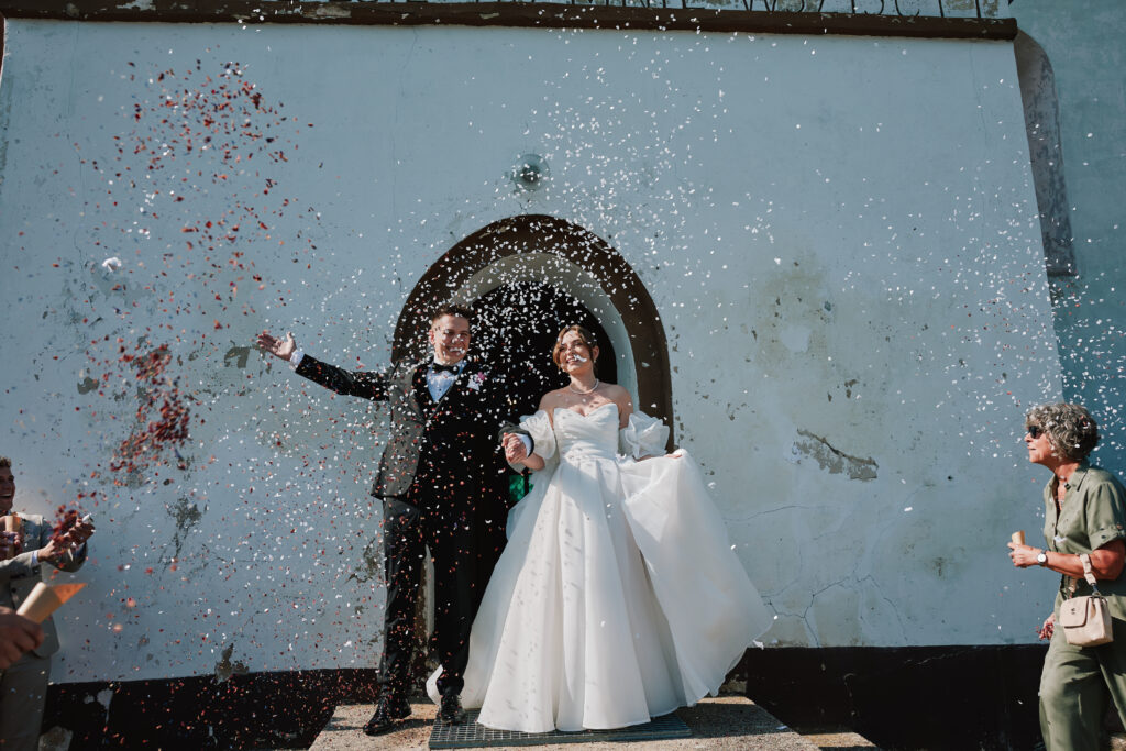 Przepiękne ujęcie pary młodej podczas ślubu, otoczonej bankietem konfetti i gośćmi, w stylowym studio.