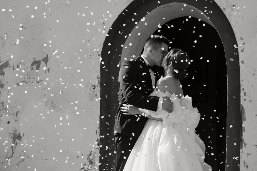 Alt tekst: para młoda w romantycznym uścisku podczas ślubu, w czerni i bieli.