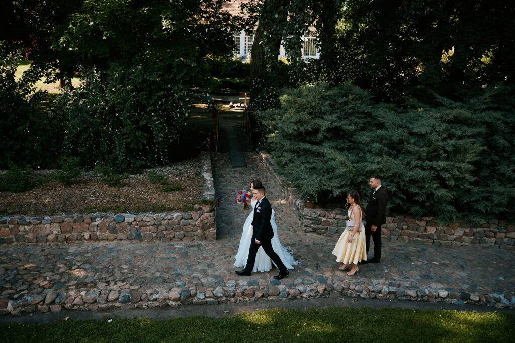 Bajkowy ślub w ogrodzie z parą młodą i gośćmi, romantyczna atmosfera na świeżym powietrzu.