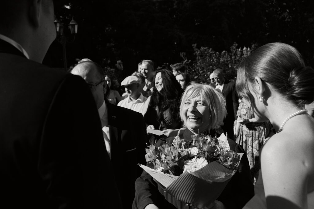 Uczestnicy wesela podczas uroczystości plenerowej, szczęśliwa pani młoda, humor i emocje, fotografia ślubna, Blizej Studio.