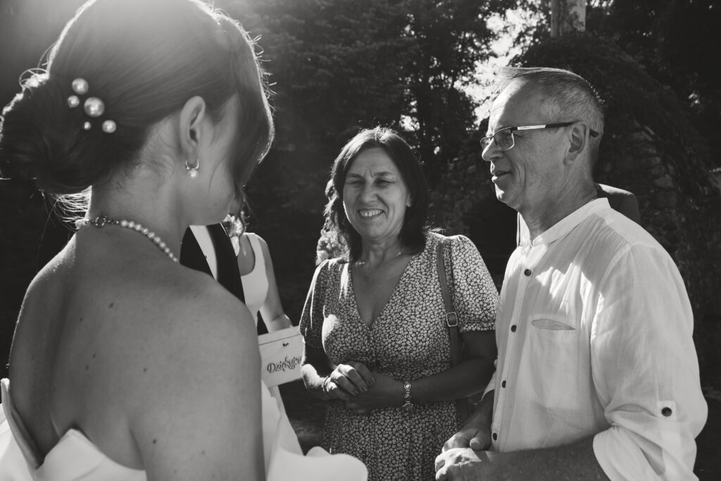 Uczestnicy ślubu rozmawiają podczas uroczystości na świeżym powietrzu.