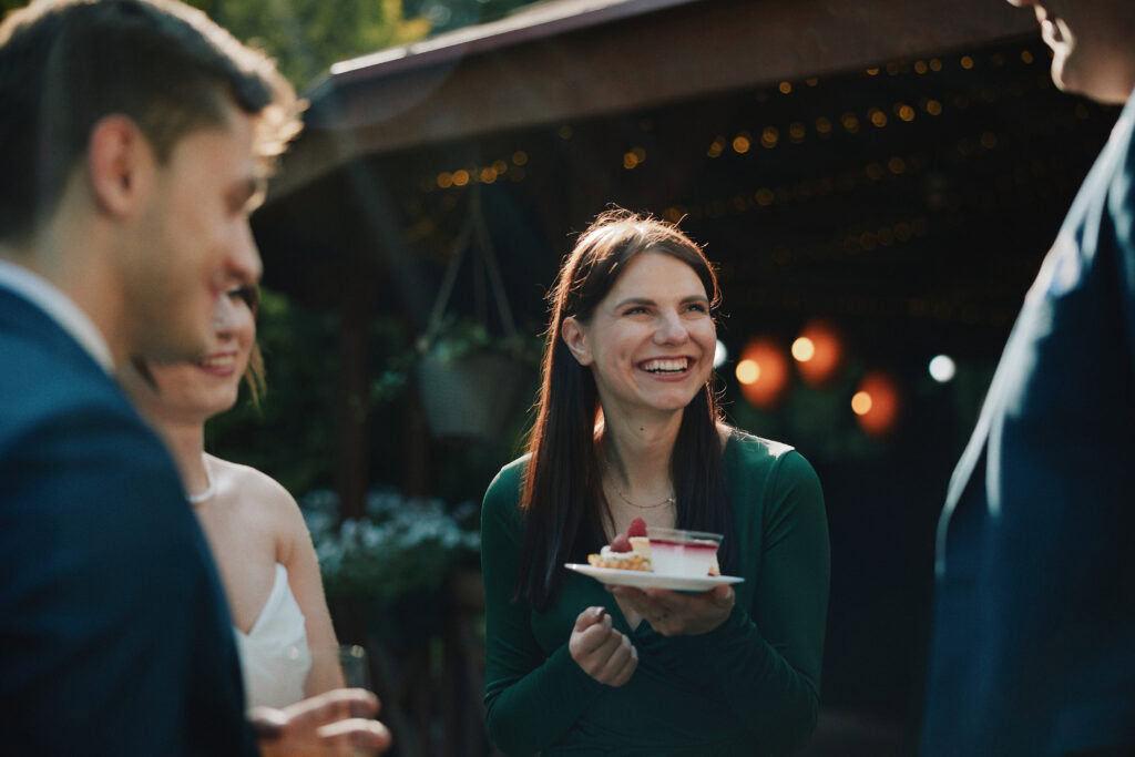 Uśmiechnięta kobieta z ciastem podczas eventu plenerowego w Blizej Studio.