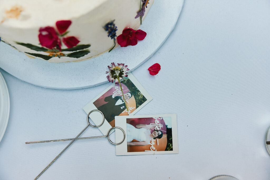 Zdjęcie ukazuje dekorację imprezową z kwiatami, skrawki tortu i fotografie z uroczystości.