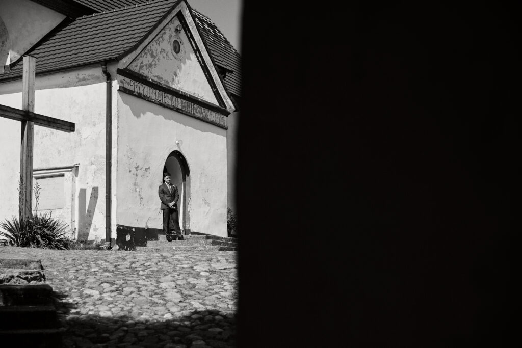 Szczegółowe zdjęcie mężczyzny w garniturze na tle starego budynku w czerni i bieli.