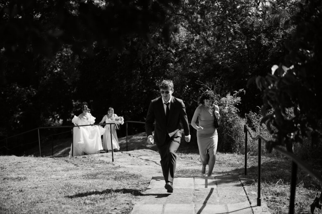 Chłopak i dziewczyna schodzą po kamiennym schodku podczas ślubu na świeżym powietrzu.