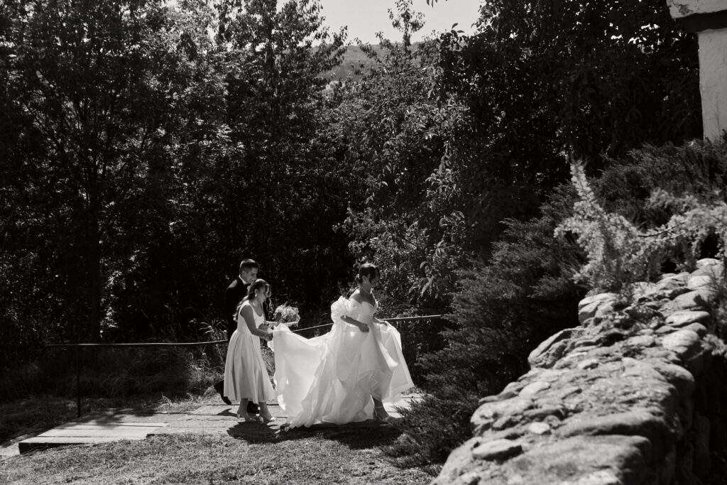 Wyjątkowa sesja ślubna w plenerze, kobieta w sukni ślubnej, drużba i dzieci, naturalne ujęcia, romantyczna atmosfera.