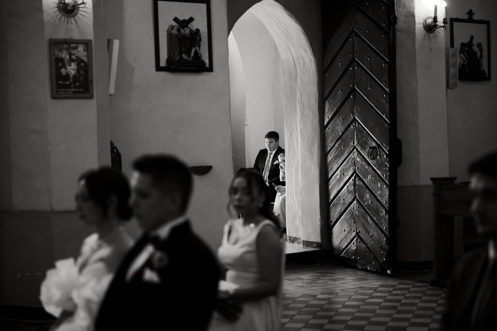 Zdjęcie konkursowe z ceremonii ślubnej w kościele, romantyczne ujęcie w czerni i bieli.